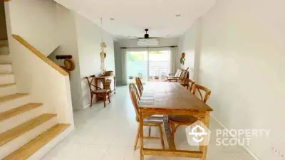 Spacious dining area with wooden table and chairs, bright natural light, and modern decor.