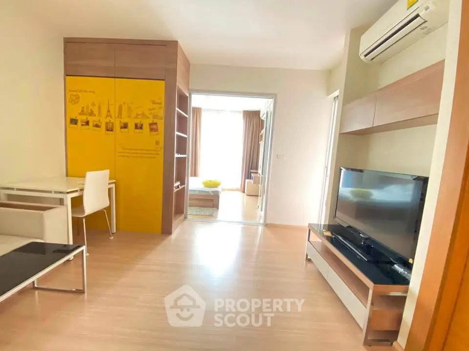 Modern living room with sleek furniture and bright natural light, featuring a TV and air conditioning.