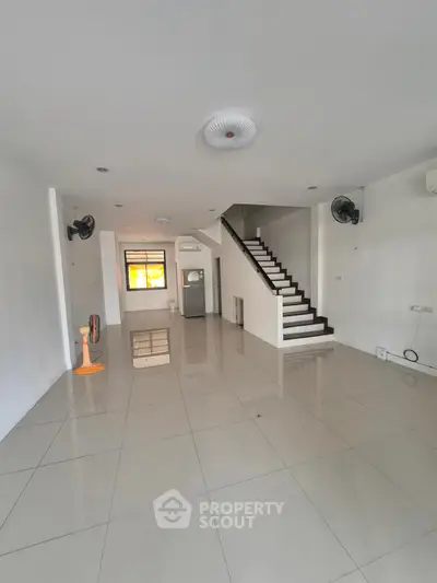 Spacious open-plan living area with modern staircase and tiled flooring