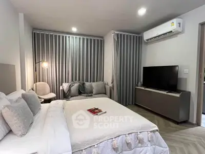 Modern bedroom with cozy decor, featuring a comfortable bed, stylish seating, and a sleek TV setup.