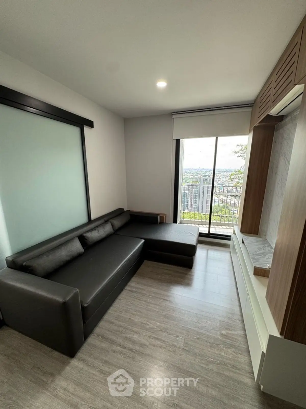 Modern living room with sleek black sofa and large window offering city view