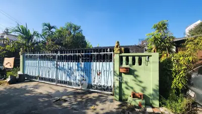 Charming gated entrance with lush greenery and decorative ironwork under a clear blue sky.