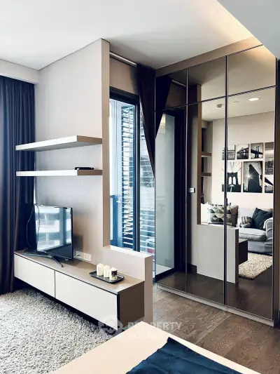 Modern living room with sleek furniture and large mirror, featuring a cozy TV setup and stylish decor.