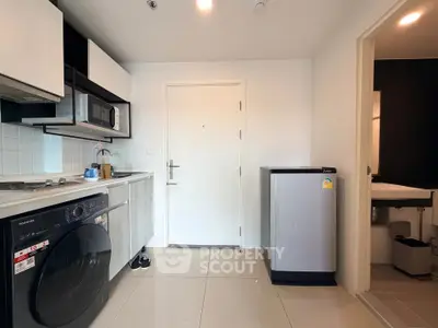 Modern kitchen with washing machine and compact fridge in sleek apartment