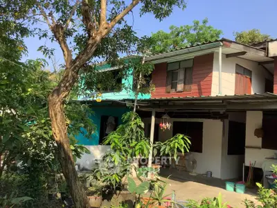 Charming two-story house with lush garden and vibrant exterior colors, perfect for nature lovers.