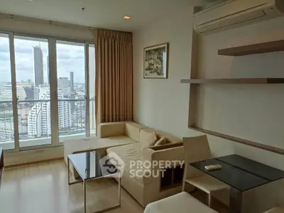 Modern living room with city view, featuring a cozy beige sofa, sleek glass table, and wall-mounted air conditioner.