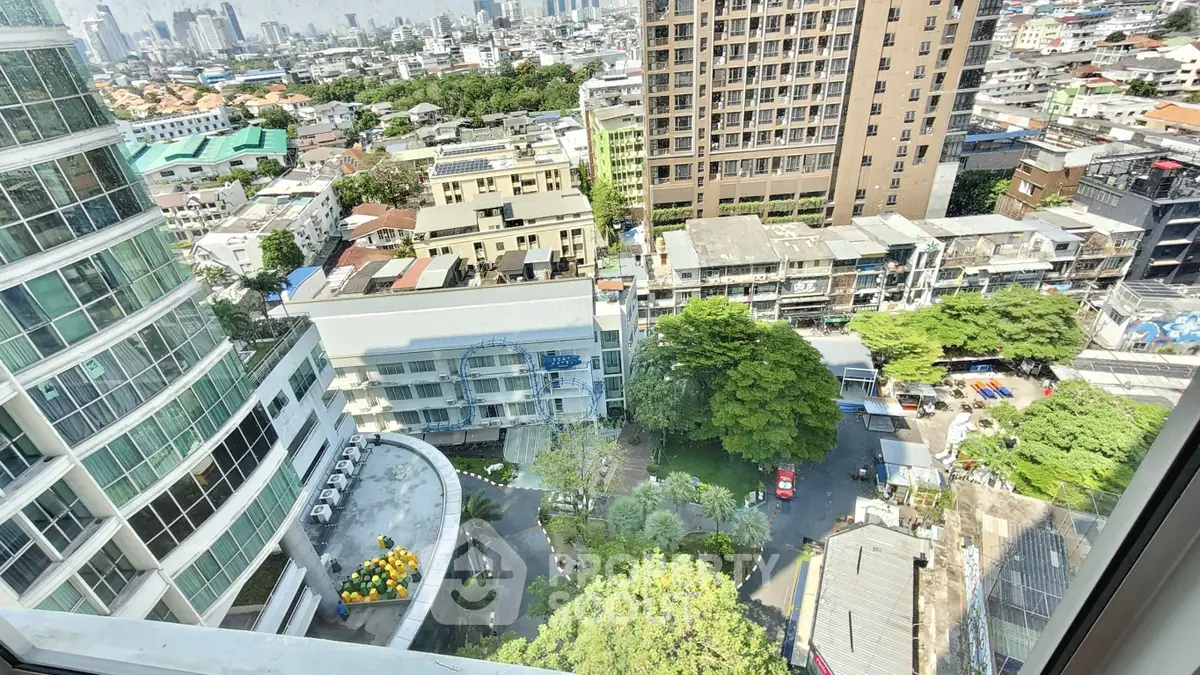 Stunning urban view from high-rise apartment window overlooking cityscape and greenery.