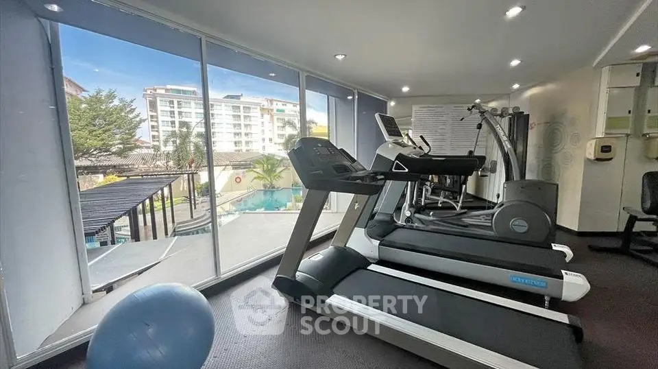 Modern gym with treadmills and pool view in luxury apartment complex