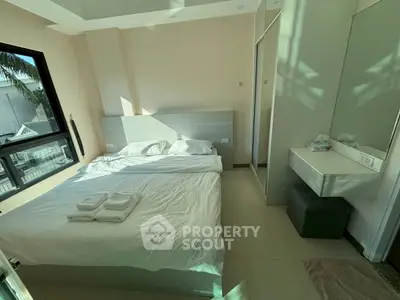 Bright and cozy bedroom with modern furnishings and large window view.