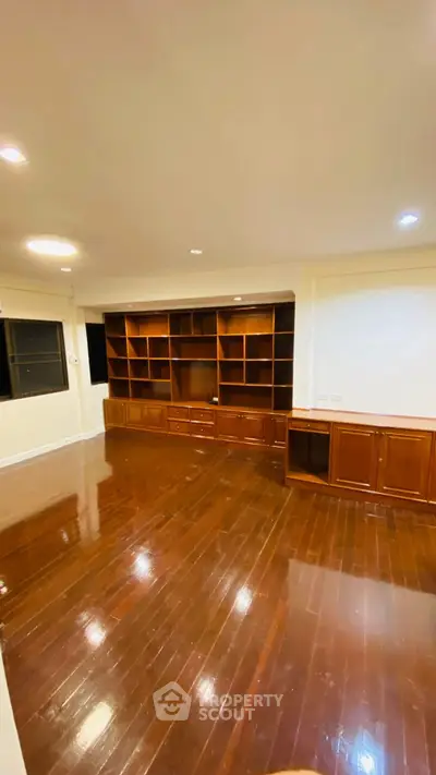Spacious living room with polished wooden floors and built-in shelving unit.