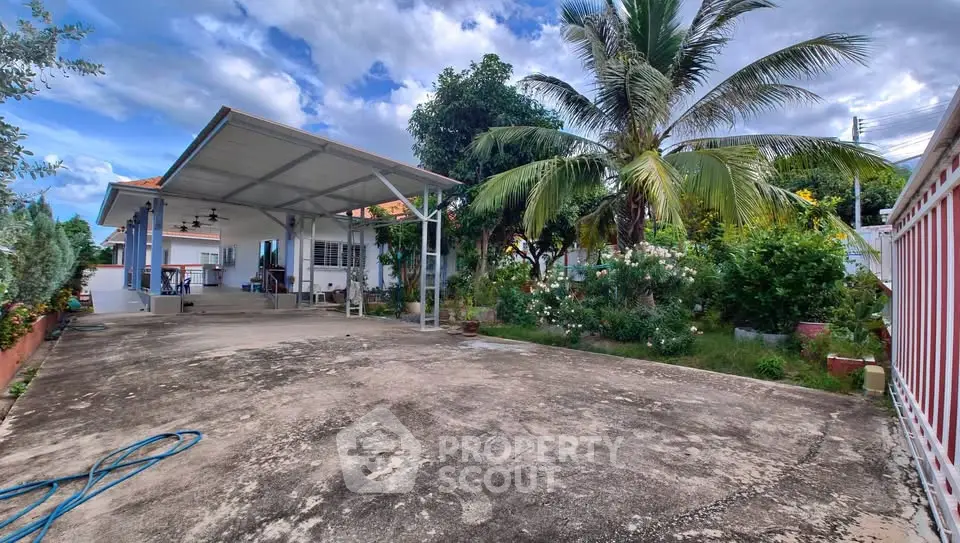 Spacious tropical home with lush garden and covered parking area, perfect for family living.