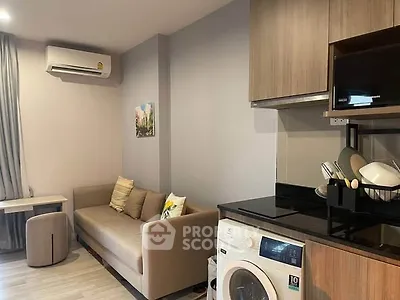 Modern living room with cozy sofa, air conditioning, and compact kitchen featuring washing machine and microwave.