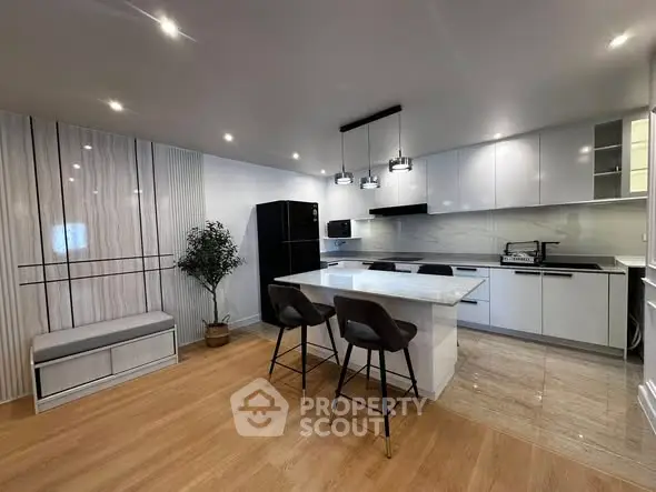 Modern kitchen with sleek design, featuring an island, stylish lighting, and high-end appliances.
