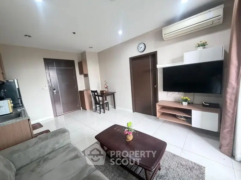 Modern living room with sleek furniture and wall-mounted TV in a cozy apartment.