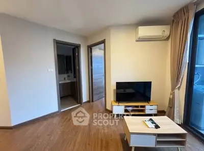 Modern living room with wooden flooring, TV setup, and air conditioning unit.