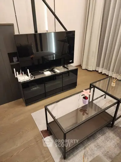 Modern living room with sleek TV stand and glass coffee table, perfect for contemporary urban living.