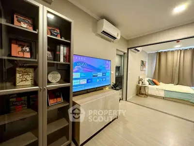 Modern living room with TV and air conditioning, leading to a cozy bedroom.