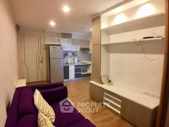 Modern living room with open kitchen and stylish purple sofa