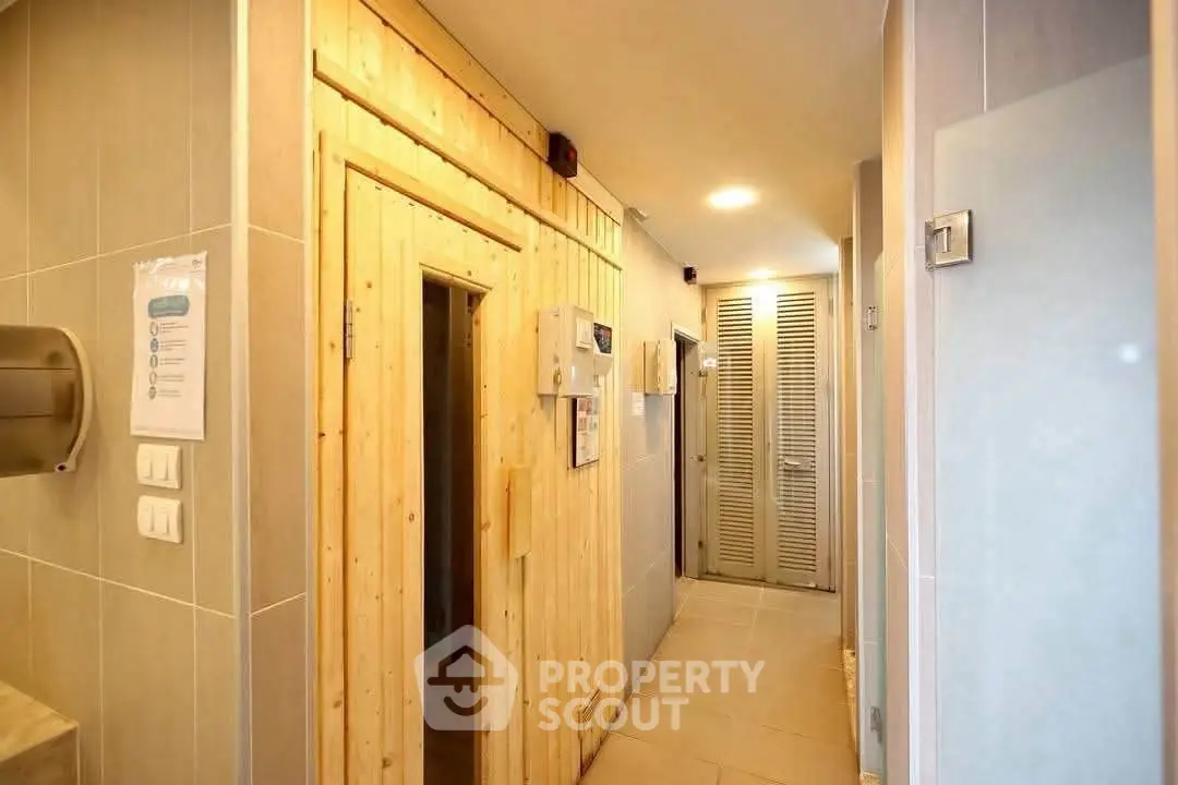 Modern hallway with wooden sauna door and sleek tile design in a residential building.