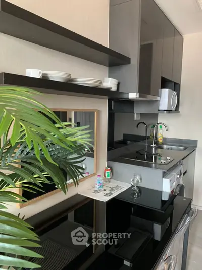 Modern kitchen with sleek black countertops and built-in appliances, featuring open shelving and stylish decor.