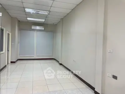 Spacious empty room with tiled flooring and large windows, ideal for office or retail space.