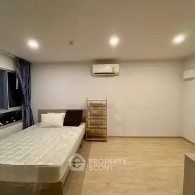 Spacious minimalist bedroom with natural light and modern air conditioning.