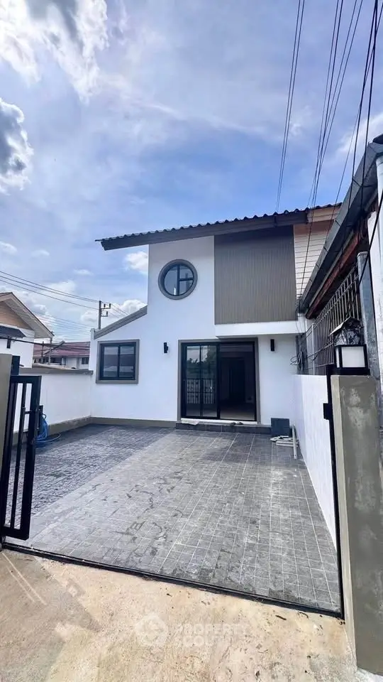 Modern two-story house with unique circular window and spacious driveway.
