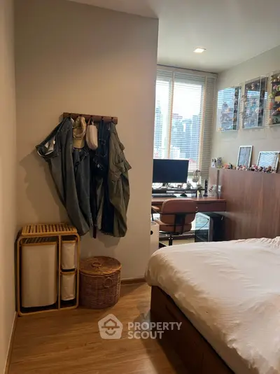 Cozy bedroom with study area, featuring wooden flooring and ample natural light from large windows.