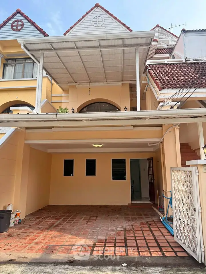 Charming townhouse with covered carport and tiled driveway in a serene neighborhood.