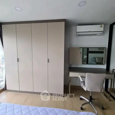 Modern bedroom with sleek wardrobe and study desk, featuring air conditioning and stylish decor.