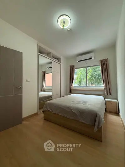 Cozy bedroom with large window and built-in wardrobe in modern apartment