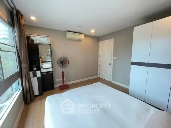 Spacious bedroom with modern decor and large window for natural light.
