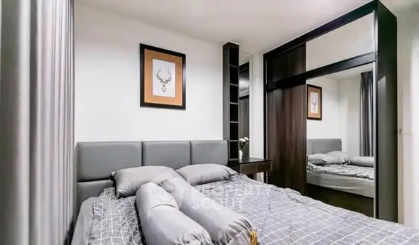 Modern bedroom with stylish decor and mirrored wardrobe in a cozy apartment.