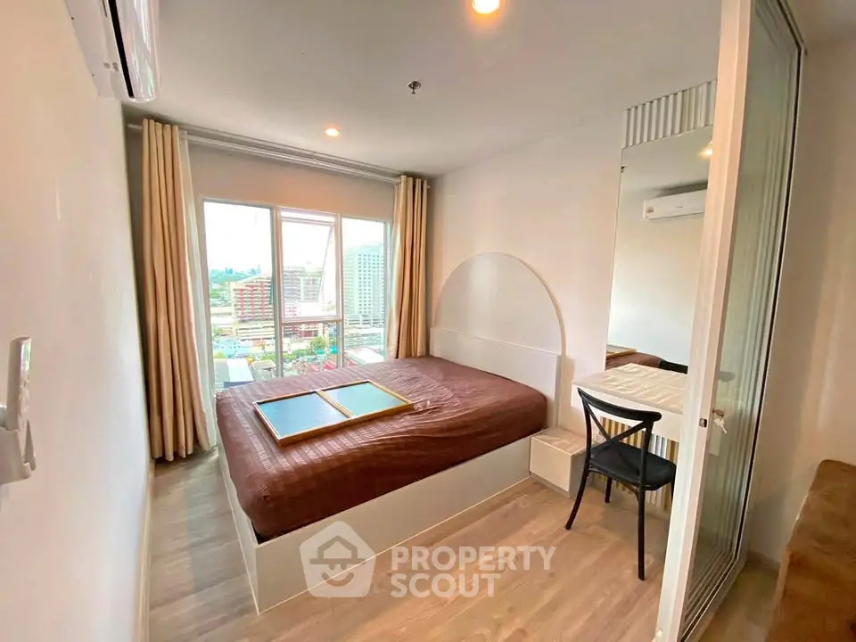Modern bedroom with city view, featuring a cozy bed and stylish decor in a high-rise apartment.