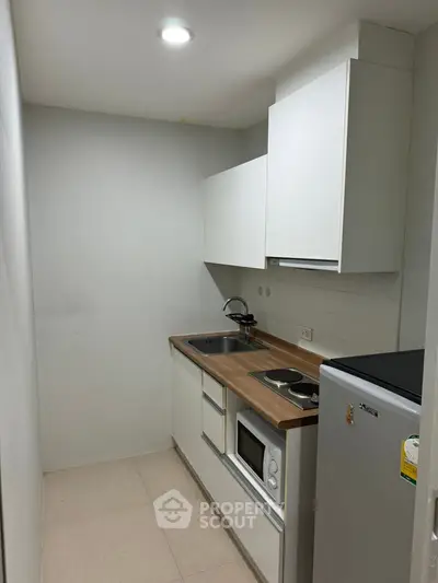 Compact modern kitchen with sleek cabinetry and essential appliances in a cozy apartment.