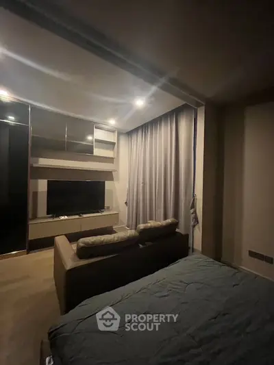 Cozy bedroom with modern TV setup and elegant lighting, perfect for relaxation.
