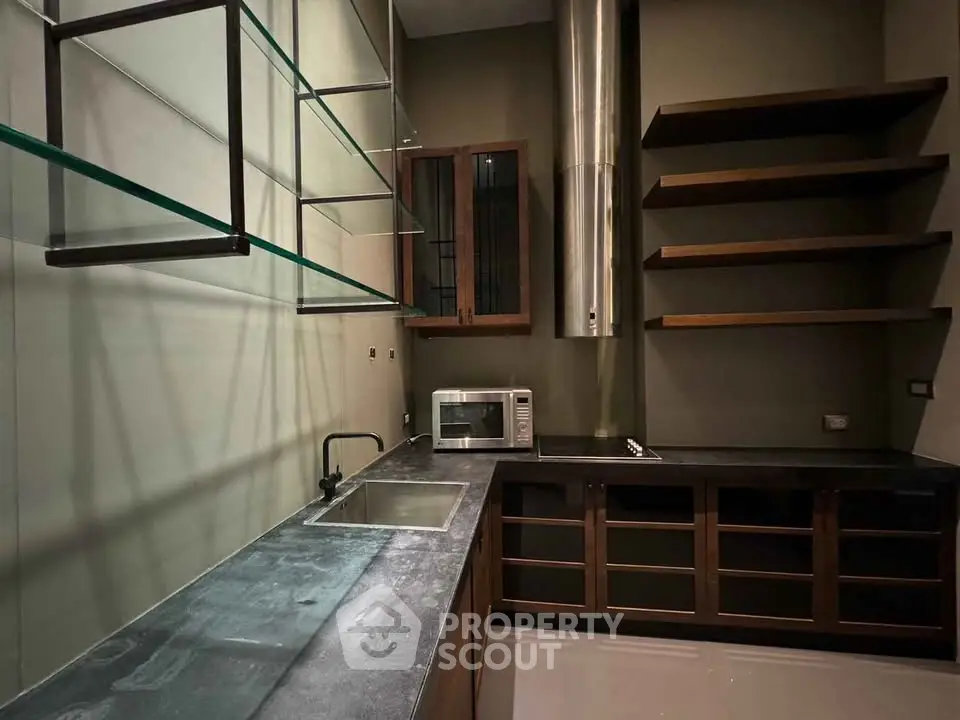 Modern kitchen with sleek countertops and open shelving, featuring a built-in microwave and stainless steel accents.