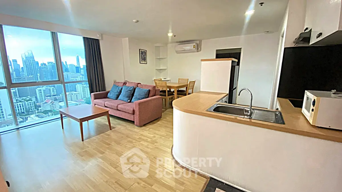 Spacious modern living room with city view, open kitchen, and dining area in high-rise apartment.