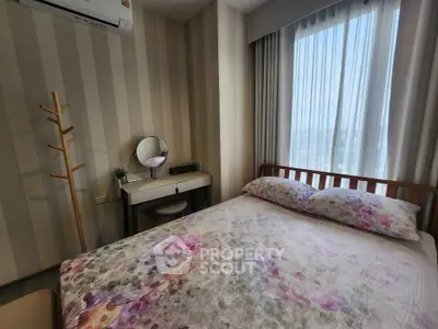 Cozy bedroom with floral bedding, striped wallpaper, and natural light from large window.