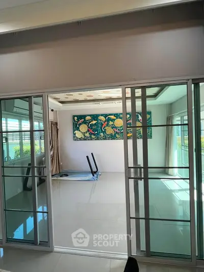 Spacious room with sliding glass doors and modern art, ideal for versatile living space.