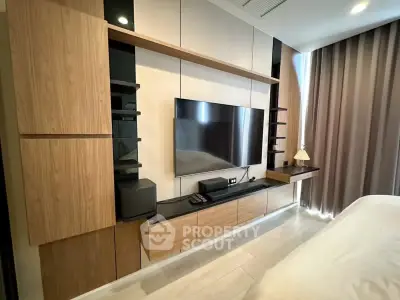 Modern bedroom with sleek wooden entertainment unit and large TV