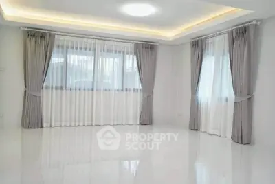 Spacious and bright empty living room with elegant curtains and glossy floors.