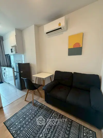 Modern living room with compact kitchen, featuring a cozy sofa and stylish decor.