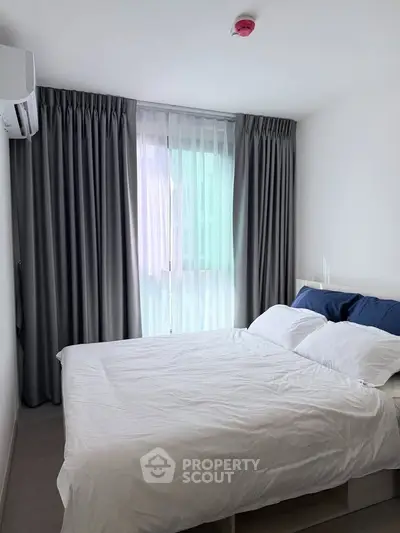 Cozy bedroom with modern decor and natural light, featuring a comfortable bed and elegant curtains.
