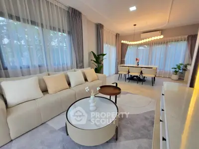 Elegant living room with modern decor and dining area, featuring large windows and stylish lighting.