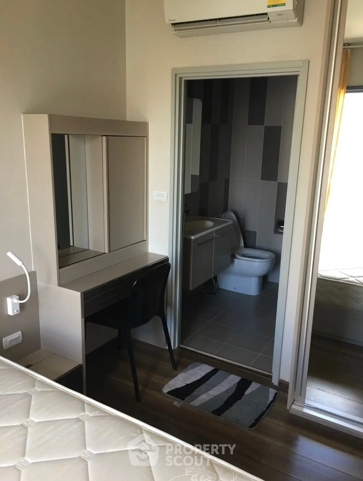 Modern bedroom with ensuite bathroom and study area, featuring sleek furniture and air conditioning.