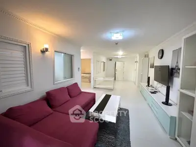 Spacious living room with modern decor and vibrant red sofa, perfect for relaxation and entertainment.