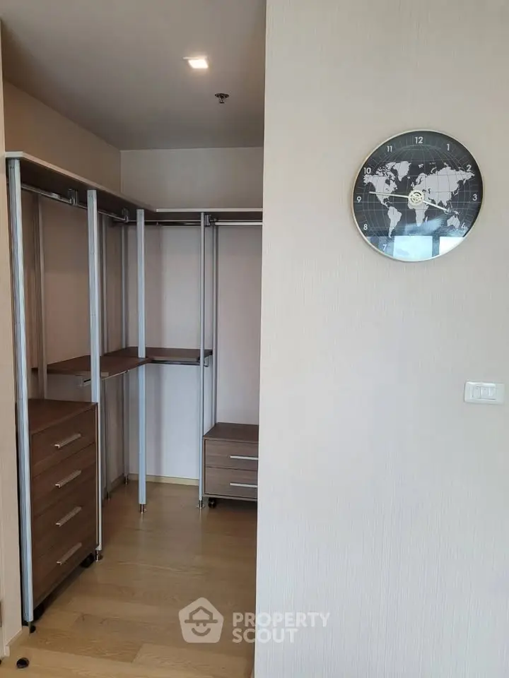 Spacious walk-in closet with modern wooden shelving and world map clock.