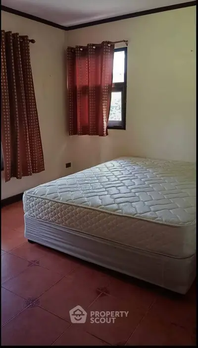 Cozy bedroom with natural light and simple decor, featuring a comfortable mattress and elegant curtains.