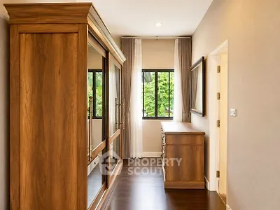 Elegant bedroom with wooden wardrobe and dresser, featuring large windows and natural light.